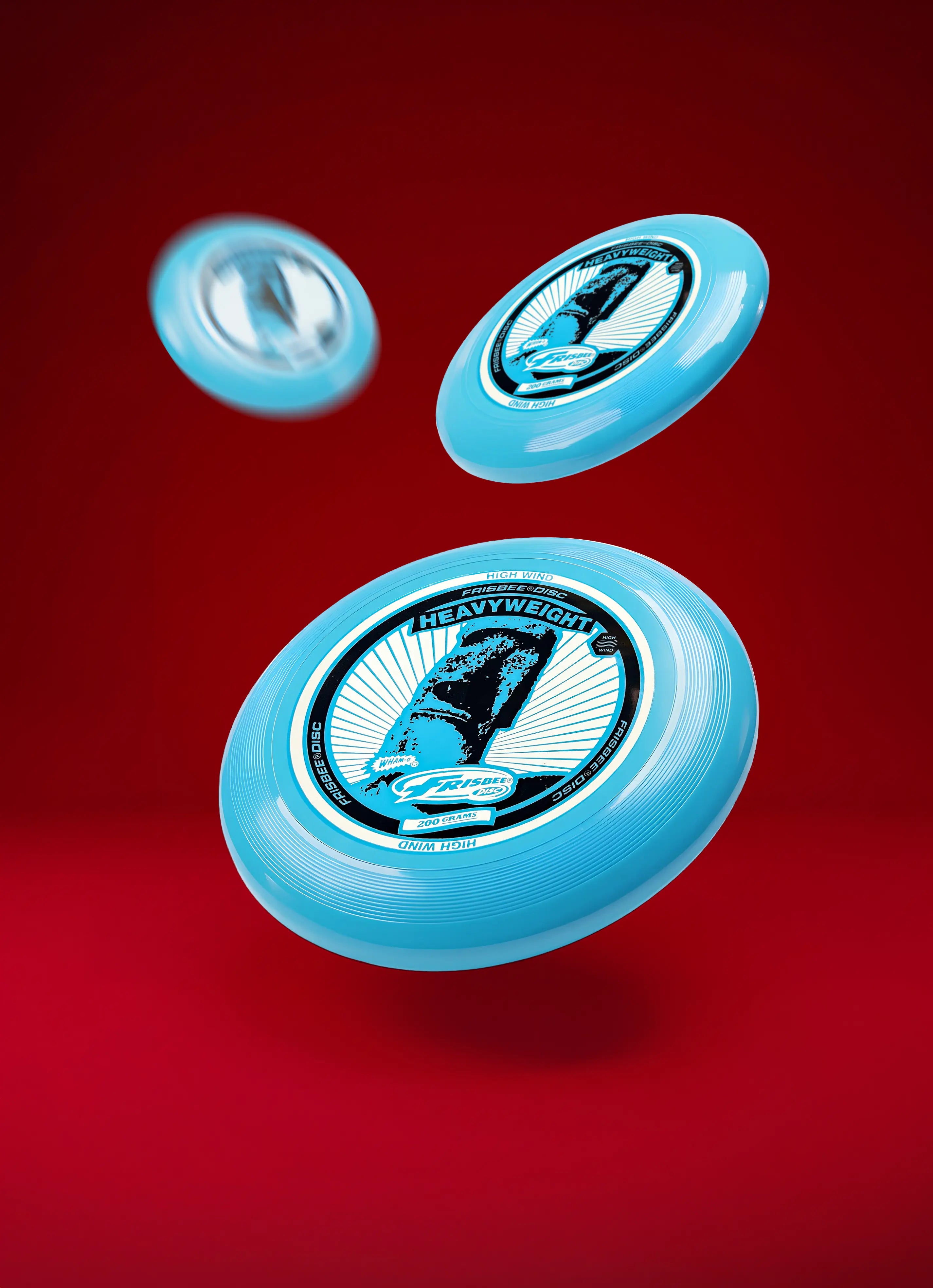 Floating blue heavyweight flying disc with black graphics on a red background