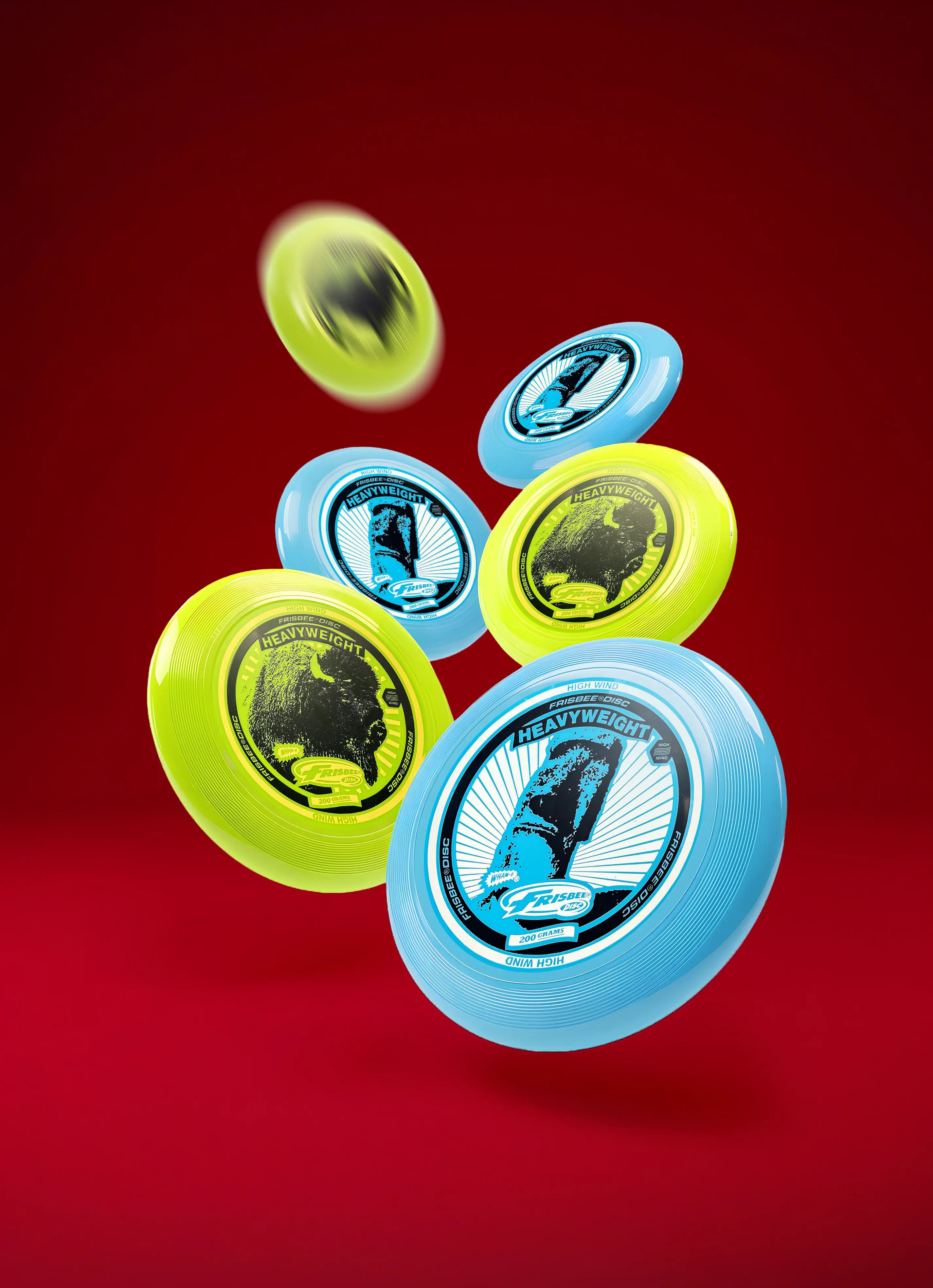 Blue and yellow heavyweight Frisbee discs floating against a red background