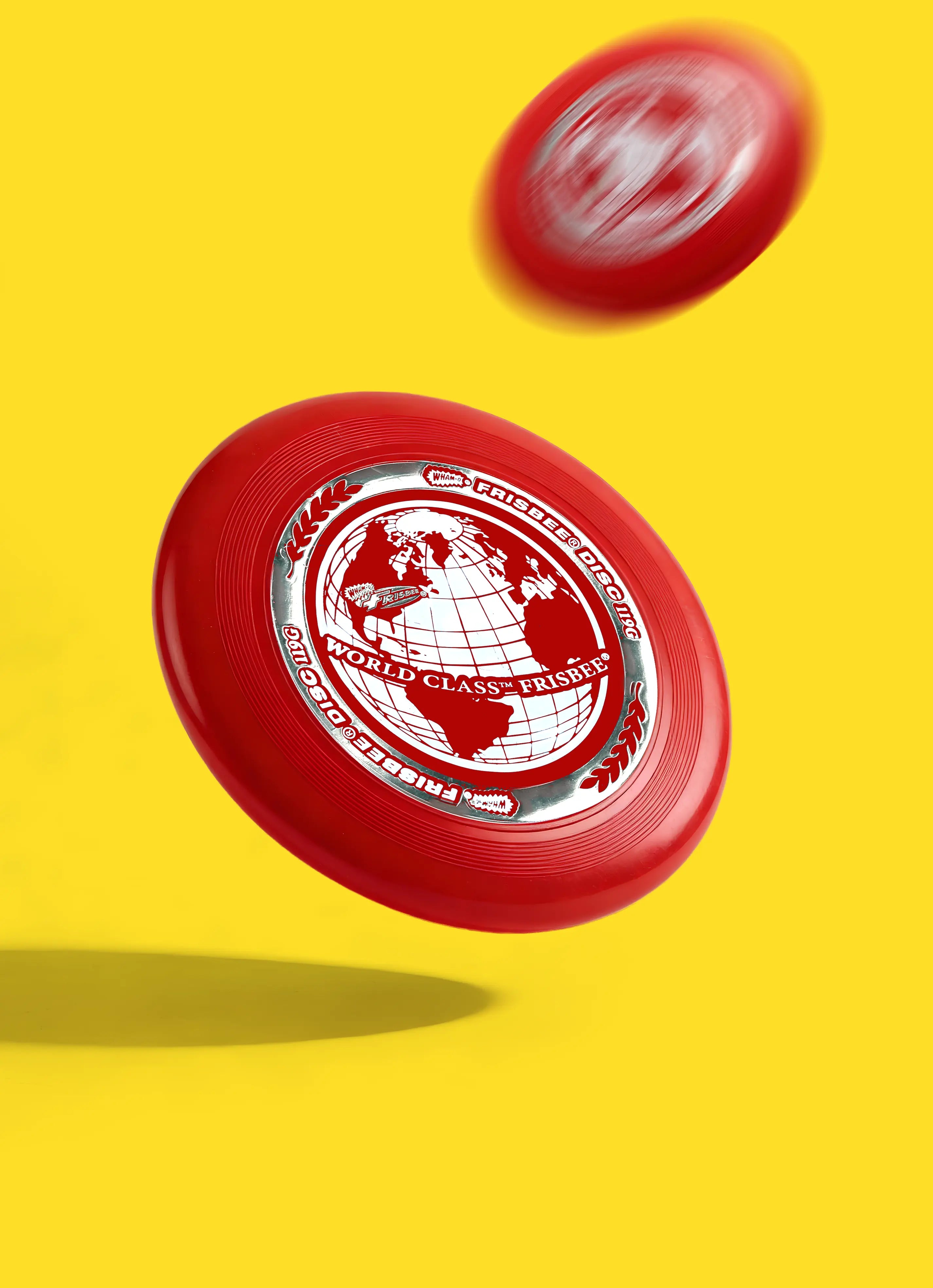 Red World Class Frisbee disc with globe design on yellow background, in midair