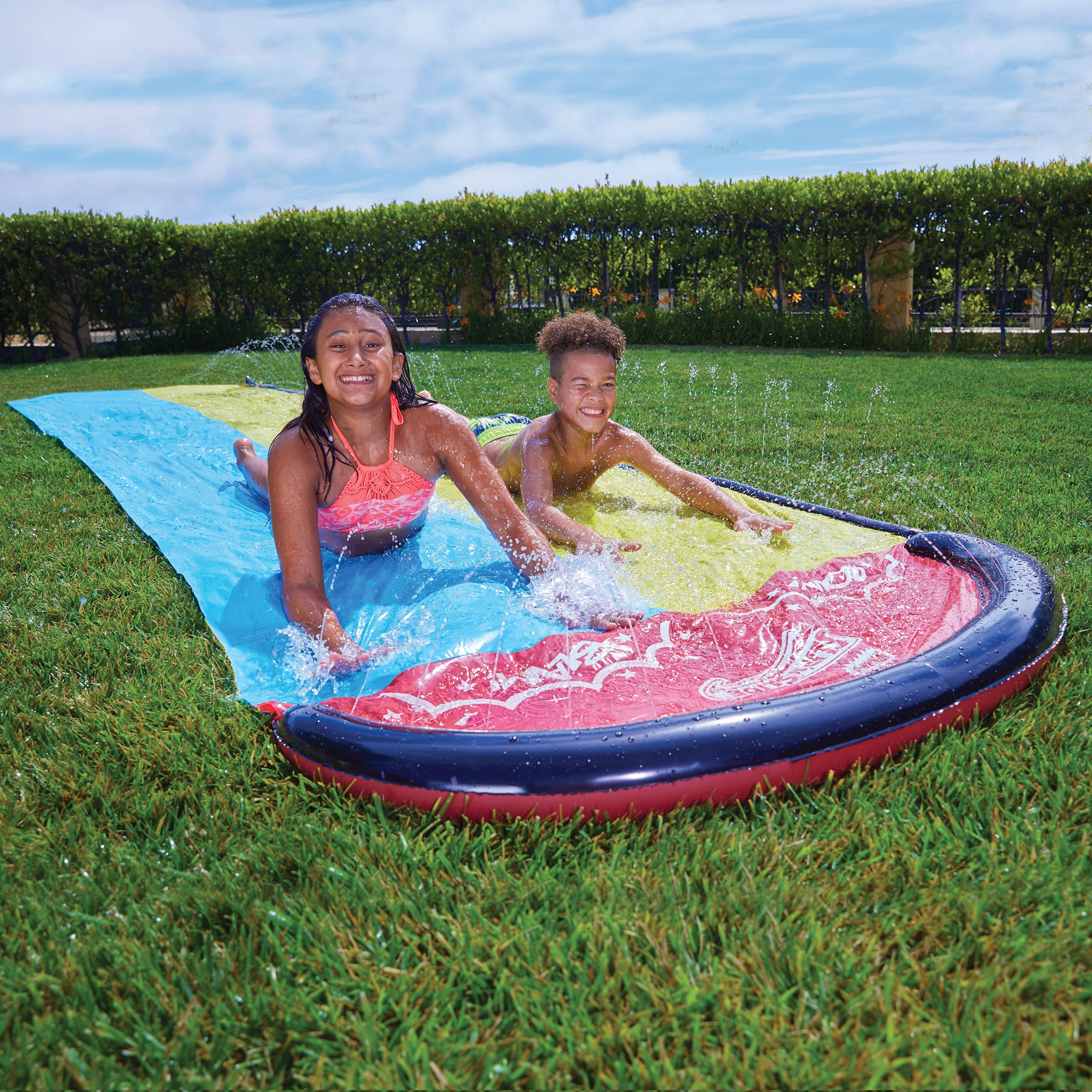 Children are having fun with Wham-O Slip 'N Slide® Double Wave Rider® in the garden