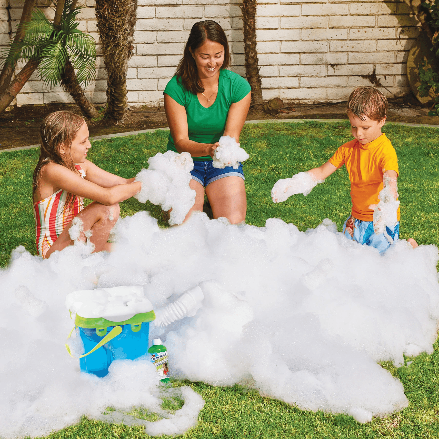 Kids and adult playing with outdoor bubble machine on green grass in backyard