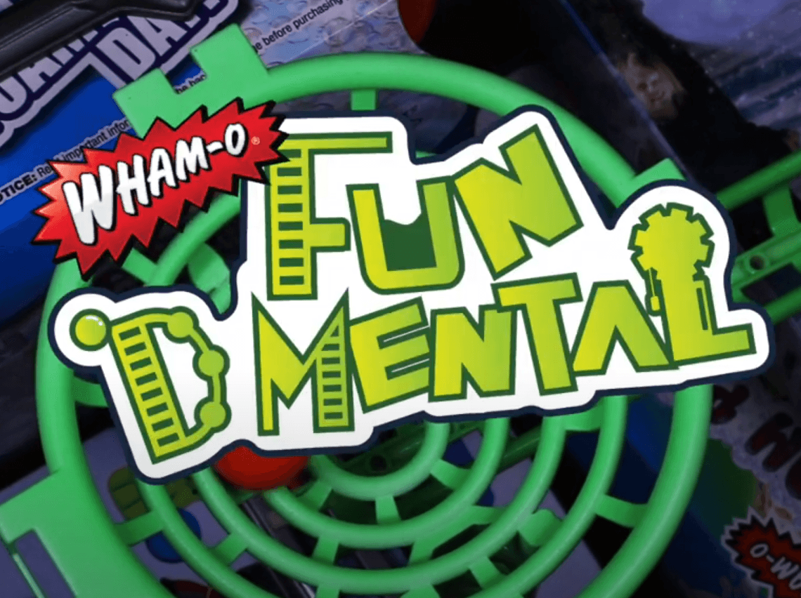 Wham-O Fun D Mental green plastic toy part with colorful logo and packaging background