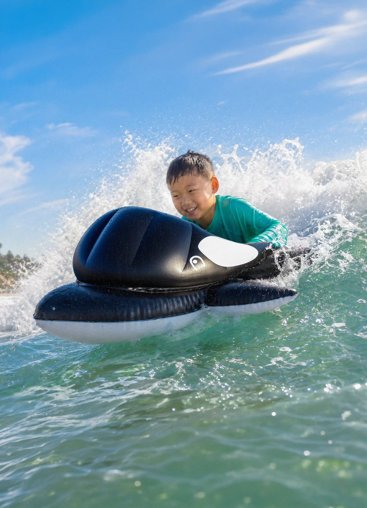 A young boy riding a Boogie Board Orca Wave Catcher through ocean waves.
