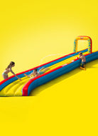 Kids playing on inflatable Slip 'n Slide water slide with arch on bright yellow background