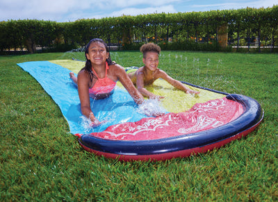 Children are having fun with Wham-O Slip 'N Slide® Double Wave Rider® in the garden