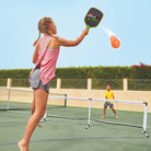 Sister and young brother are playing with Wham-O Game Time! Pickleball Game Set in the backyard