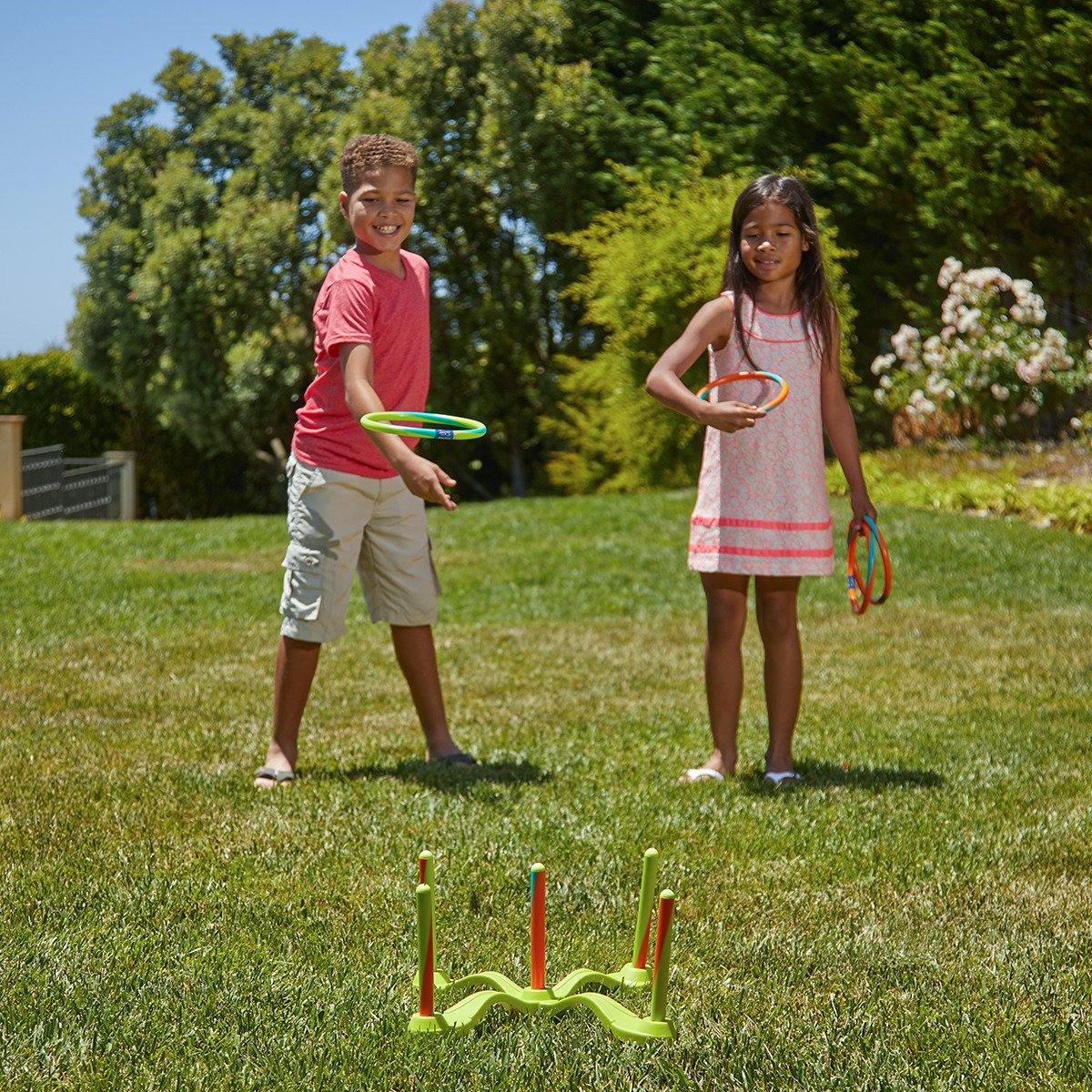 Young kids are playing with Wham-O Game Time! Hula Hoop® Ring Toss in the backyard
